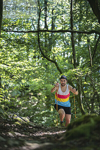 Mann mit Wanderstock beim Wandern auf einem Bergpfad im Wald