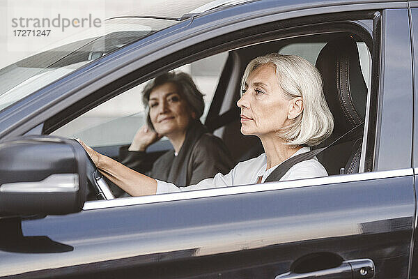 Kollege sitzt mit Geschäftsfrau beim Autofahren in der Stadt