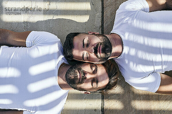 Sonnenlicht fällt auf ein schwules Paar  das sich auf dem Gehweg entspannt