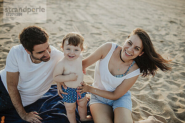Lächelnde Familie mit kleinem Jungen am Strand bei Sonnenuntergang