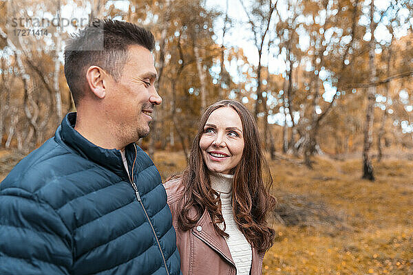 Lächelndes Paar  das sich im Herbst im Park stehend ansieht