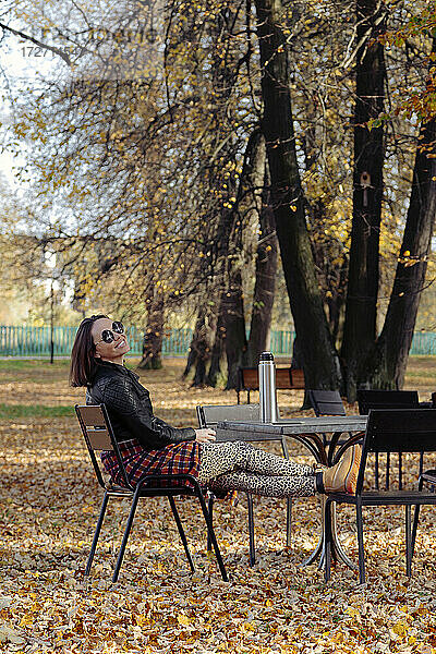 Frau mit Sonnenbrille  die an einem sonnigen Tag im Park sitzt