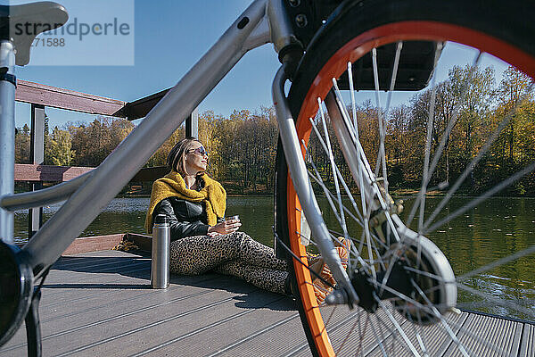 Frau entspannt sich am Wochenende mit dem Fahrrad auf dem Pier über dem See