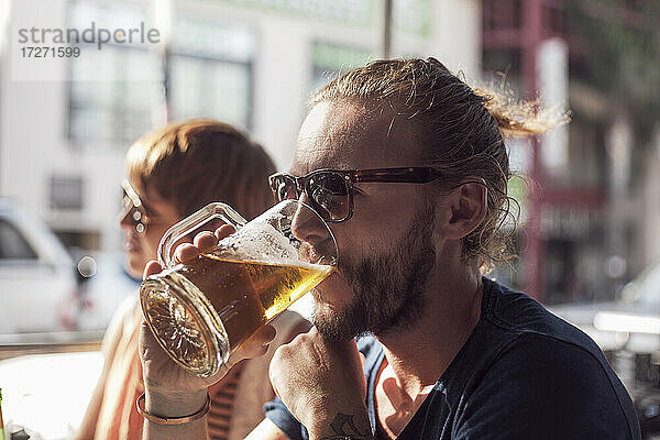 Mittlerer erwachsener Mann  der in einem Café sitzt und Bier trinkt
