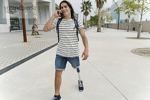 Mann mit Beinprothese telefoniert beim Spaziergang in der Stadt mit seinem Smartphone