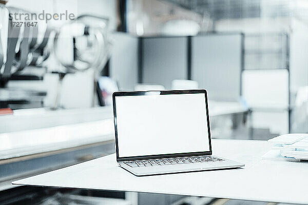 Laptop mit leerem Bildschirm auf einem Tisch in der Industrie