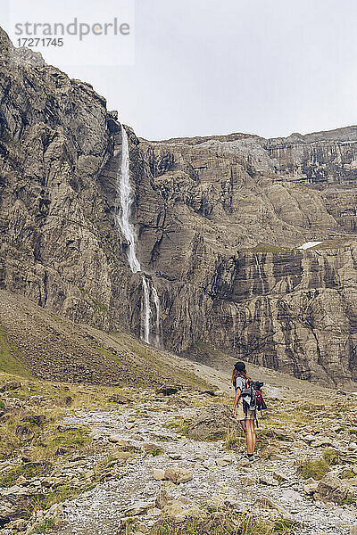 Junge Frauen bewundern die Aussicht auf einen Wasserfall  während sie vor einem Berg stehen