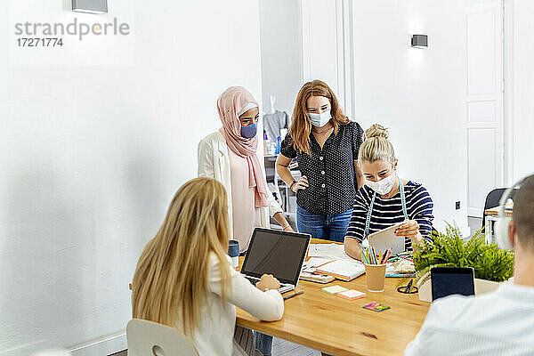 Angestellter trägt Gesichtsmaske bei der Arbeit im Büro