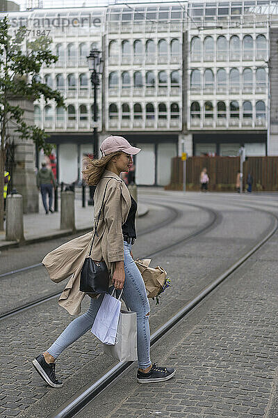 Junge Frau mit Einkaufstaschen beim Überqueren von Bahngleisen