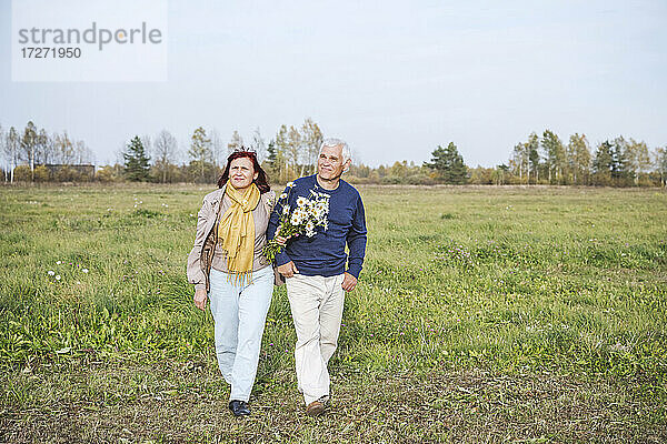 Älteres Paar mit Blumen auf einem Feld gegen den Himmel