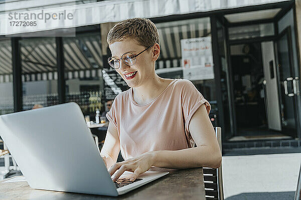Frau mit Laptop in einem Straßencafé an einem sonnigen Tag
