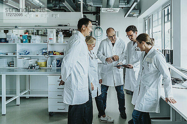 Ein Team von Wissenschaftlern mit digitalem Tablet arbeitet im Labor zusammen