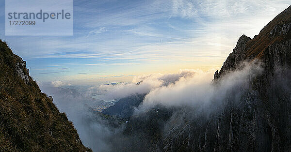 Idyllische Aufnahme eines von Wolken bedeckten Berges bei Sonnenaufgang in den Bergamasker Alpen  Italien