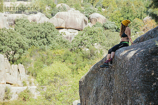 Wanderer betrachtet die Aussicht  während er sich auf einem Felsen im Wald bei La Pedriza  Madrid  Spanien  ausruht