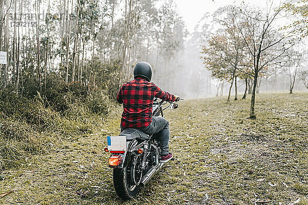 Mann beim Motorradfahren im Wald bei nebligem Wetter
