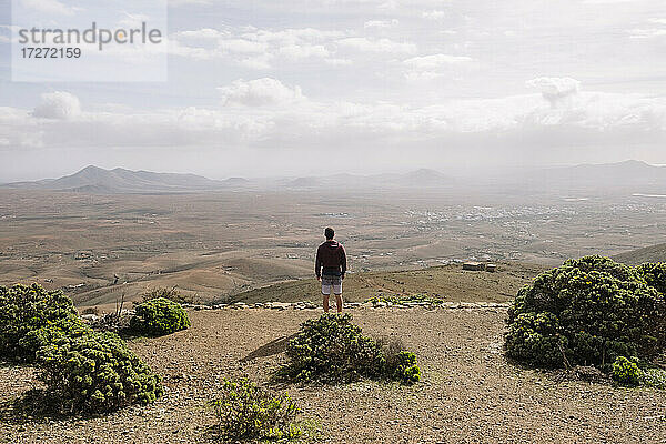Mittlerer erwachsener Mann  der auf einem Hügel stehend die Aussicht betrachtet
