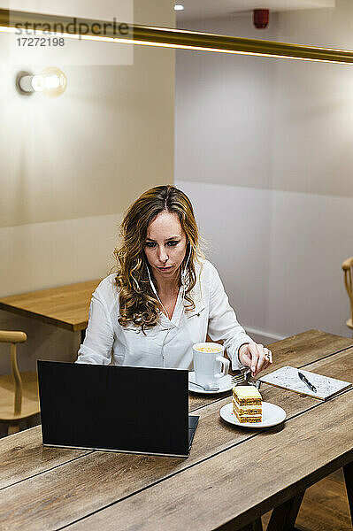 Geschäftsfrau  die einen Laptop benutzt  während sie am Tisch Kaffee trinkt