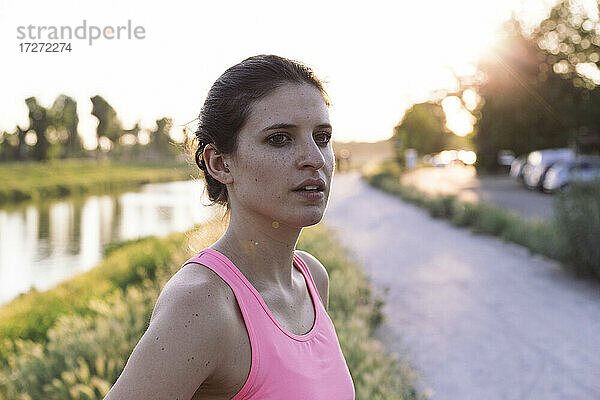 Selbstbewusste Sportlerin  die bei Sonnenuntergang im Park steht und wegschaut