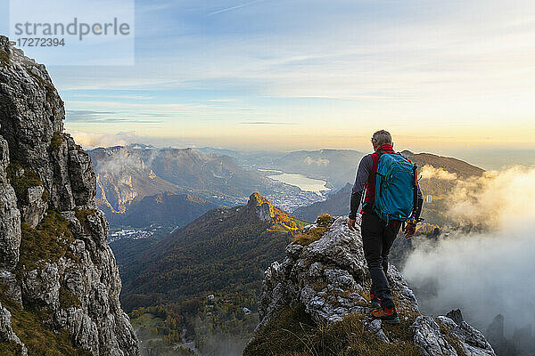 Nachdenklicher männlicher Wanderer bei Sonnenaufgang auf einem Berggipfel in den Bergamasker Alpen  Italien