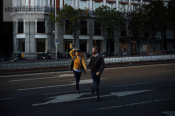 Ehemann und Ehefrau halten sich an der Hand  während sie die Straße in der Stadt überqueren