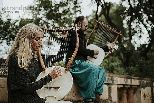 Frau mit Mann spielt Lyra-Musikinstrument auf Bank