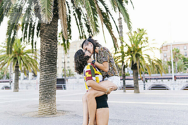 Junge Frau trägt Freundin und küsst auf der Straße in der Stadt