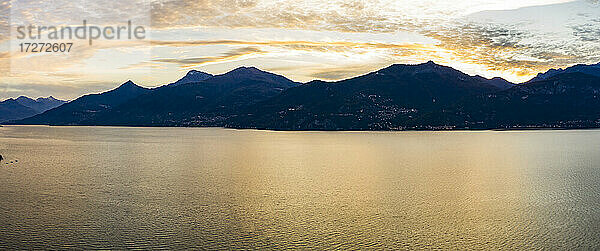 Blick aus dem Hubschrauber auf den Comer See in der Morgendämmerung mit Silhouetten der Berge im Hintergrund