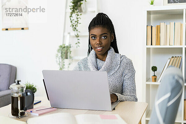Junge Frau  die zu Hause sitzend am Laptop lernt