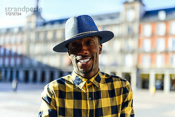 Lächelnder afrikanischer Mann mit Hut in der Stadt stehend