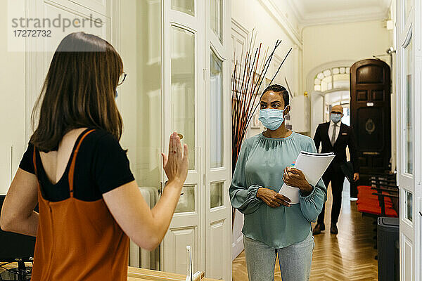 Weibliche Geschäftsfrau mit Gesichtsschutzmaske im Korridor hält an