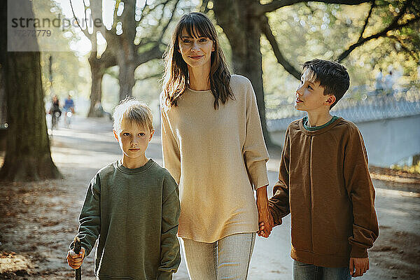 Mutter und Söhne spazieren im öffentlichen Park an einem sonnigen Tag