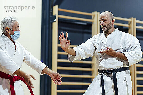 Männlicher Schüler übt Karate mit seinem Ausbilder im Unterricht