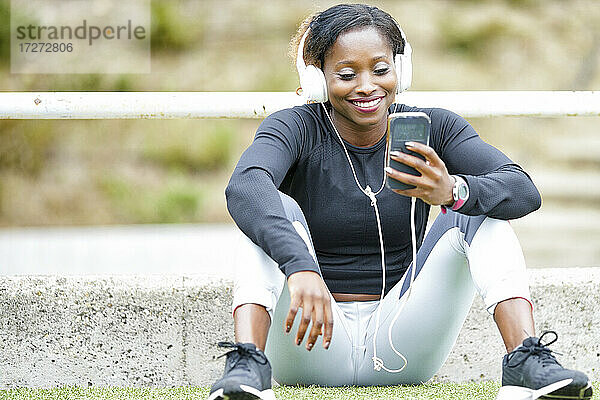 Lächelnde Sportlerin  die mit ihrem Smartphone Musik hört