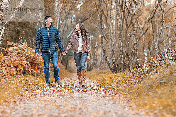 Glückliches heterosexuelles Paar  das im Herbst im Park spazieren geht