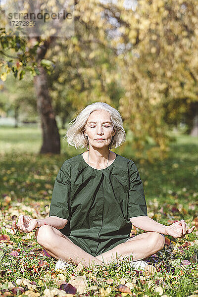 Reife Frau beim Meditieren im Park sitzend