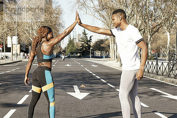 Athleten geben sich vor dem Rennen ein High Five  während sie auf der Straße in der Stadt stehen