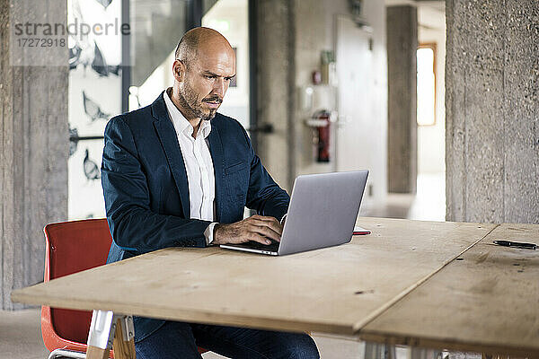 Geschäftsmann im Anzug mit Laptop bei der Arbeit im Büro