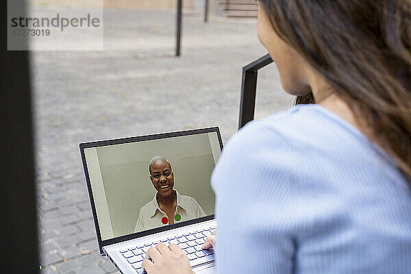 Geschäftsfrau führt Videogespräche über einen Laptop  während sie im Freien sitzt