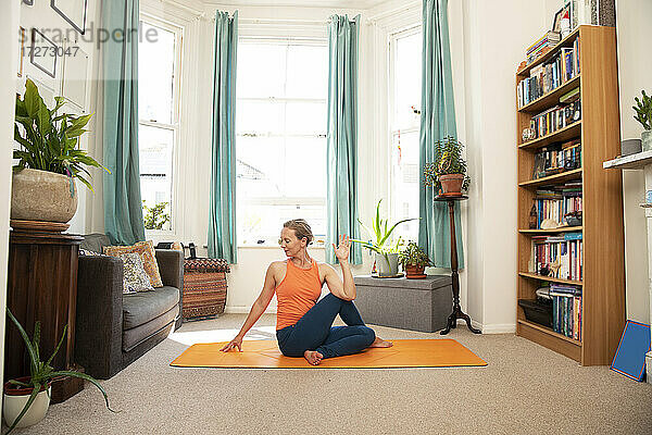 Sportlerin beim Meditieren auf einer Übungsmatte zu Hause