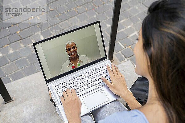 Geschäftsfrau führt Videogespräche über einen Laptop  während sie auf einer Treppe sitzt