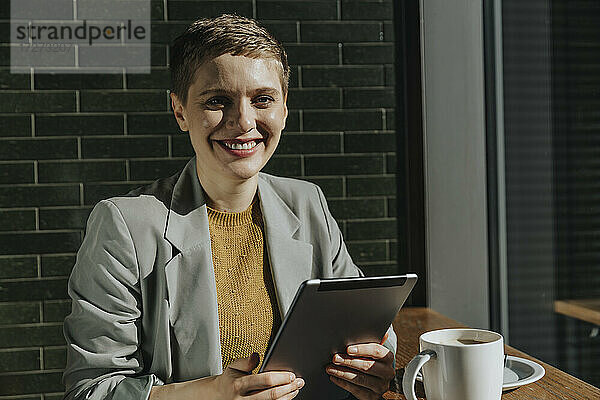 Frau benutzt digitales Tablet  während sie an einem sonnigen Tag in einem Café sitzt