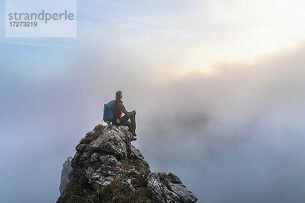 Nachdenklicher männlicher Wanderer bei Sonnenaufgang auf einem Berggipfel in den Bergamasker Alpen  Italien