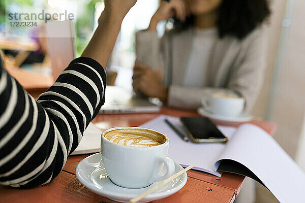 Weibliche Mitarbeiter mit Kaffeegetränk auf dem Tisch in einem Cafe