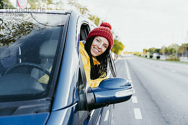 Lächelnde Frau lehnt sich während einer Autoreise an ein Autofenster
