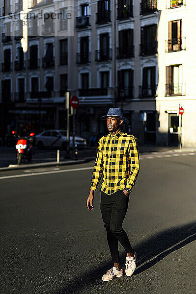 Selbstbewusster afrikanischer Mann mit Händen in den Taschen beim Spaziergang in der Stadt