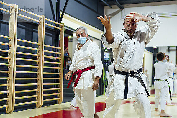 Ausbilder von männlichem Schüler  der Karate im Unterricht übt