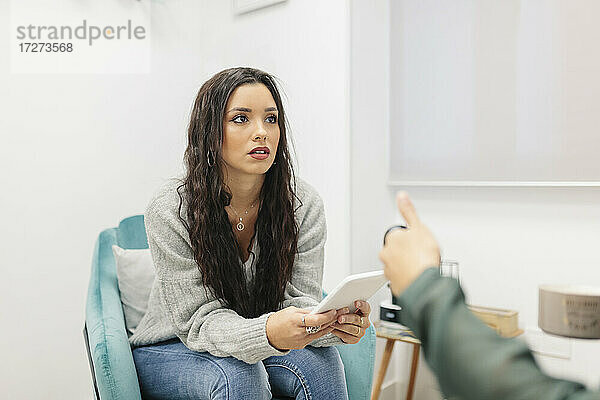 Junge Frau  die ein digitales Tablet benutzt  während sie mit einem Arzt im Büro spricht