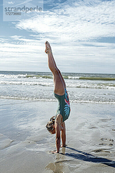 Mädchen Turner tun upside auf Sand am Strand während sonnigen Tag