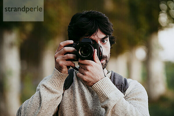 Mittlerer erwachsener Mann  der im Wald stehend ein Foto mit der Kamera macht