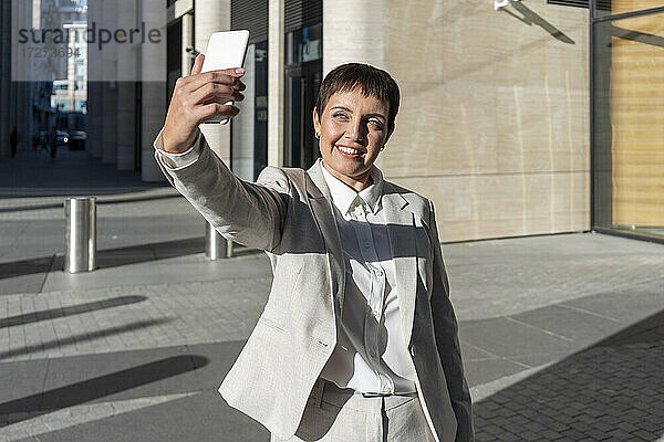 Frau nimmt Selfie  während gegen Bürogebäude stehen